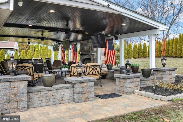 view of patio with a gazebo, a ceiling fan, and an outdoor stone fireplace