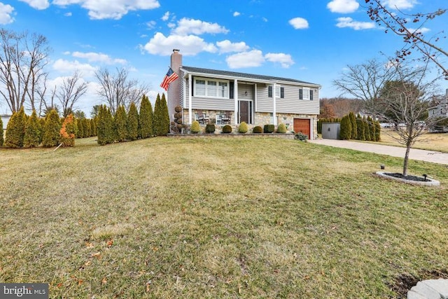 split foyer home featuring a chimney, stone siding, concrete driveway, and a front lawn