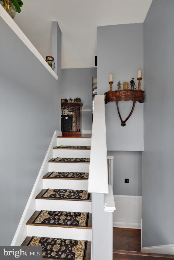 staircase featuring wood finished floors and baseboards