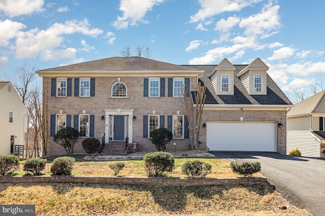 view of front of house with aphalt driveway, an attached garage, a shingled roof, and brick siding