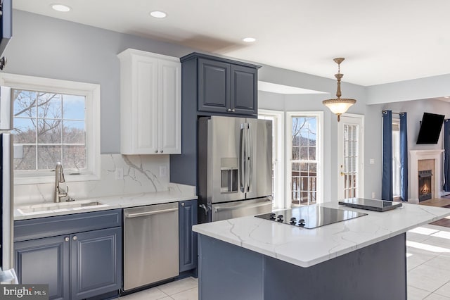 kitchen with a kitchen island, light tile patterned floors, decorative backsplash, stainless steel appliances, and a sink