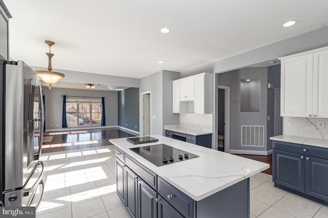 kitchen featuring light tile patterned floors, visible vents, freestanding refrigerator, black electric cooktop, and backsplash