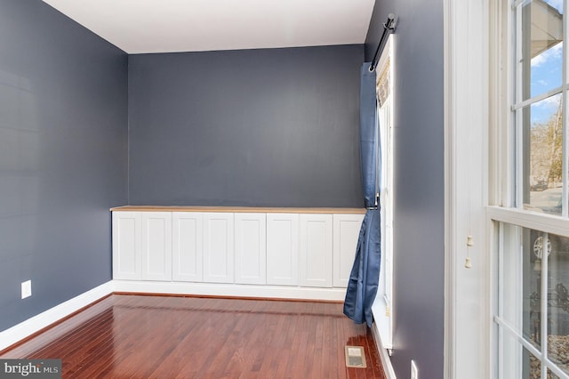 unfurnished room featuring wood finished floors, visible vents, and baseboards