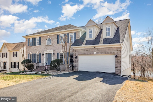 view of front of property with aphalt driveway, a garage, brick siding, and roof with shingles