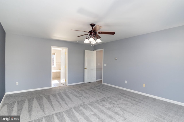 unfurnished bedroom with carpet flooring, a ceiling fan, baseboards, and connected bathroom