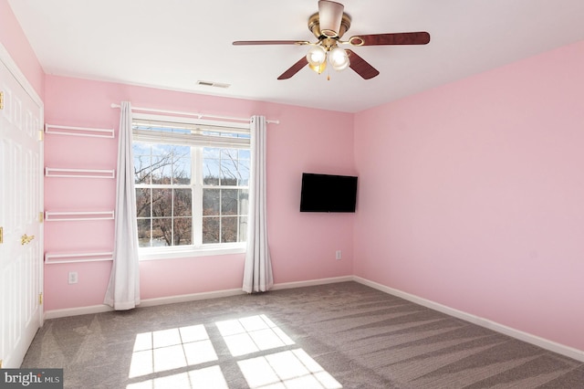 carpeted empty room with visible vents, a ceiling fan, and baseboards