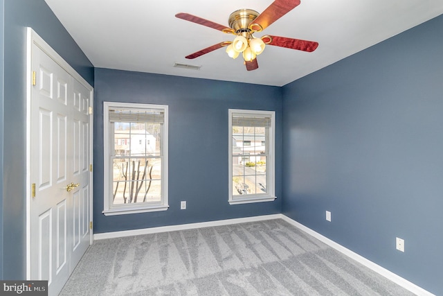 carpeted spare room with a ceiling fan, baseboards, and visible vents