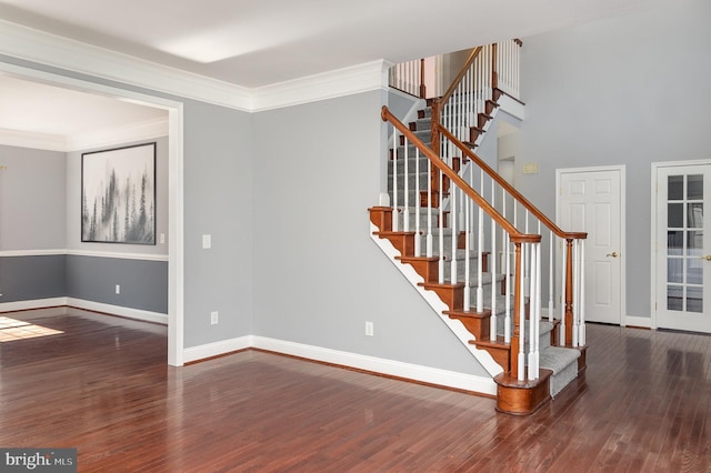 staircase featuring wood finished floors, baseboards, and ornamental molding