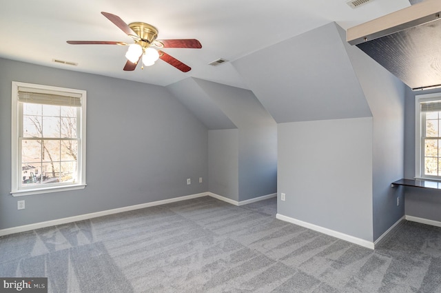 additional living space with visible vents, baseboards, carpet flooring, and vaulted ceiling