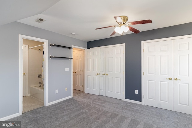 unfurnished bedroom featuring baseboards, carpet floors, two closets, and ensuite bathroom