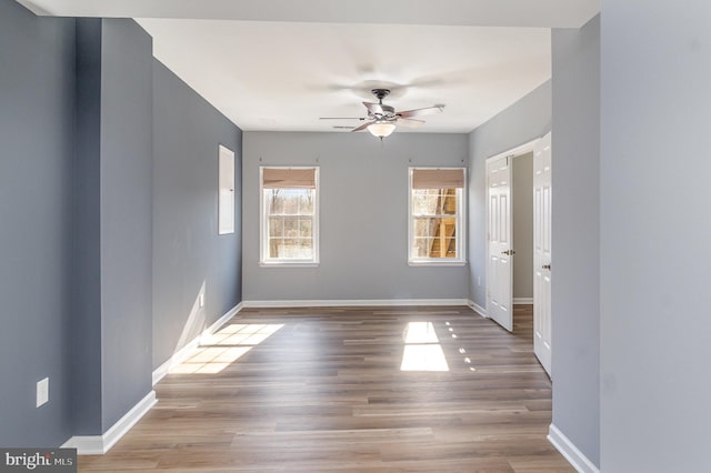 spare room featuring ceiling fan, baseboards, and wood finished floors