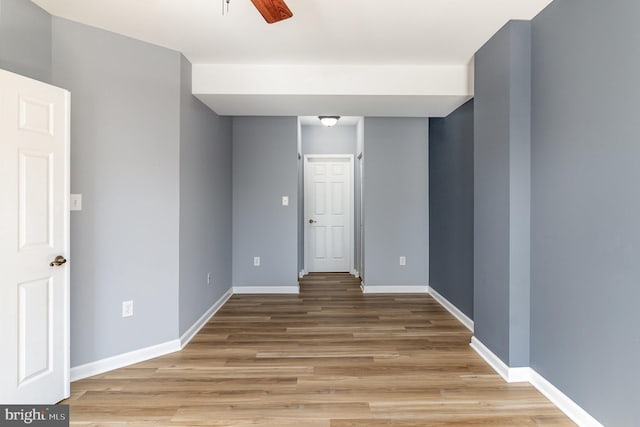 unfurnished room with light wood finished floors, ceiling fan, and baseboards