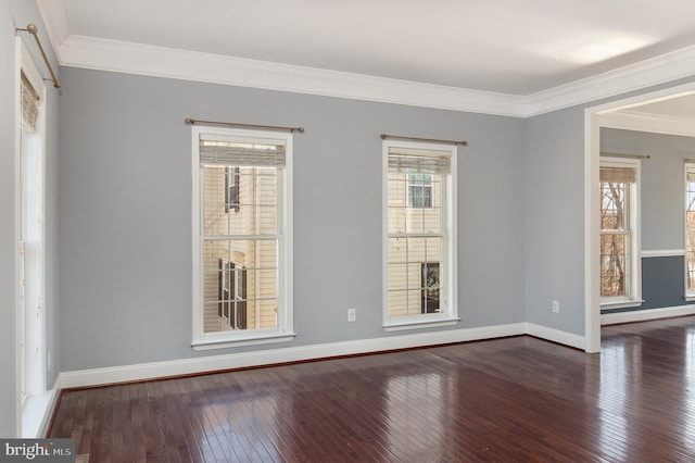 unfurnished room with dark wood-style floors, a healthy amount of sunlight, baseboards, and ornamental molding