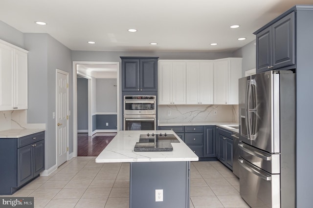 kitchen with light tile patterned floors, stainless steel appliances, tasteful backsplash, and a center island with sink