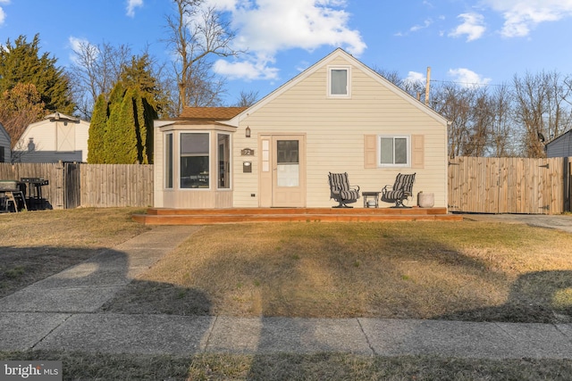 bungalow featuring a wooden deck, a front yard, and fence