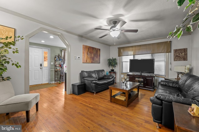 living room with a ceiling fan, arched walkways, light wood-style floors, and crown molding