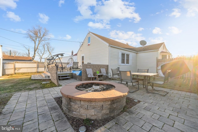 view of patio with outdoor dining space, a fenced backyard, a hot tub, and a fire pit