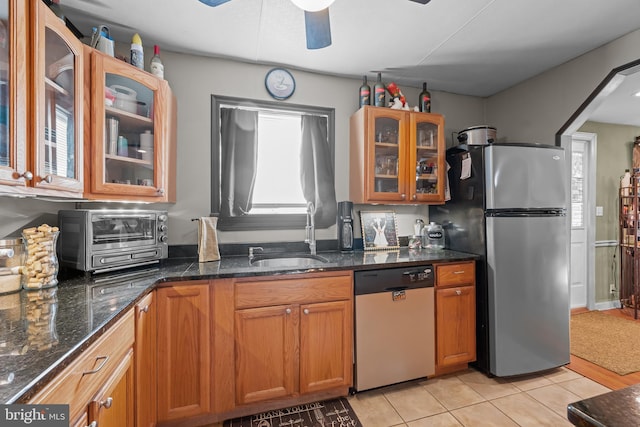 kitchen featuring glass insert cabinets, a toaster, brown cabinetry, stainless steel appliances, and a sink