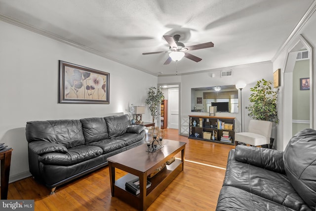 living area with visible vents, light wood-style floors, and crown molding