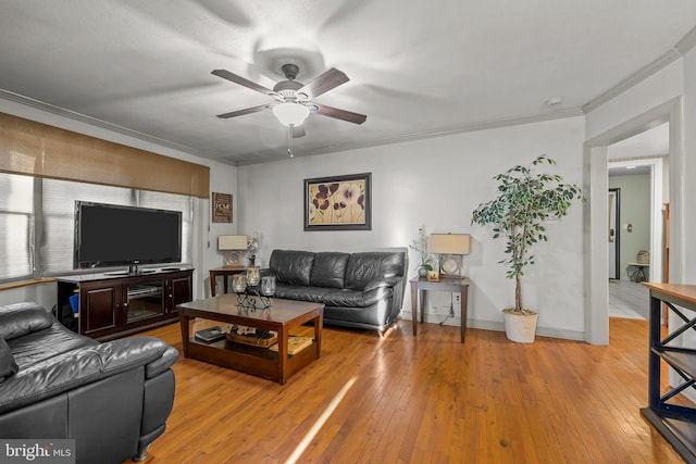 living area featuring baseboards, a ceiling fan, light wood-type flooring, and ornamental molding