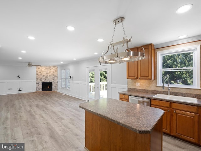 kitchen featuring a wealth of natural light, a sink, stainless steel dishwasher, dark countertops, and a center island