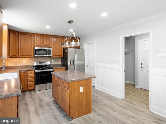 kitchen with ornamental molding, stainless steel appliances, light wood-style floors, and a sink