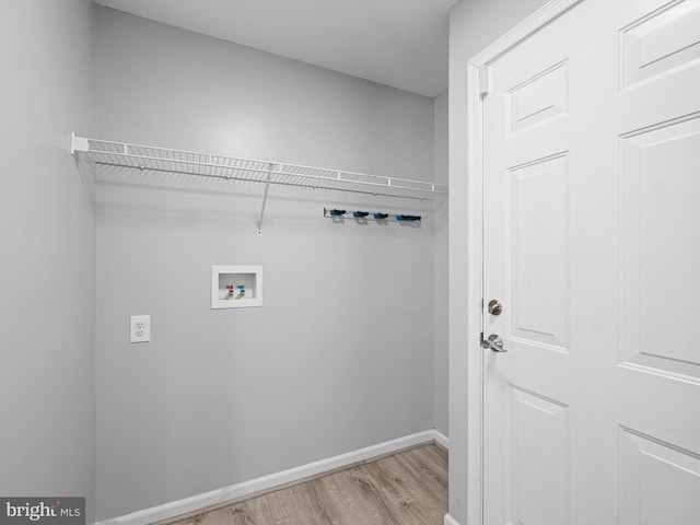 clothes washing area with hookup for a washing machine, baseboards, light wood-type flooring, and laundry area