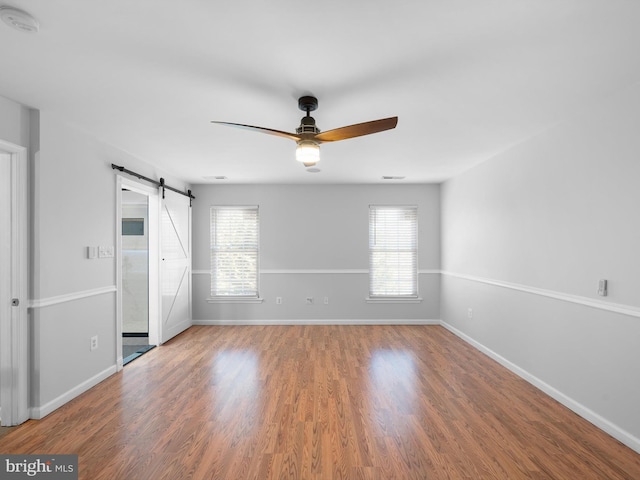 unfurnished bedroom featuring a barn door, baseboards, and wood finished floors