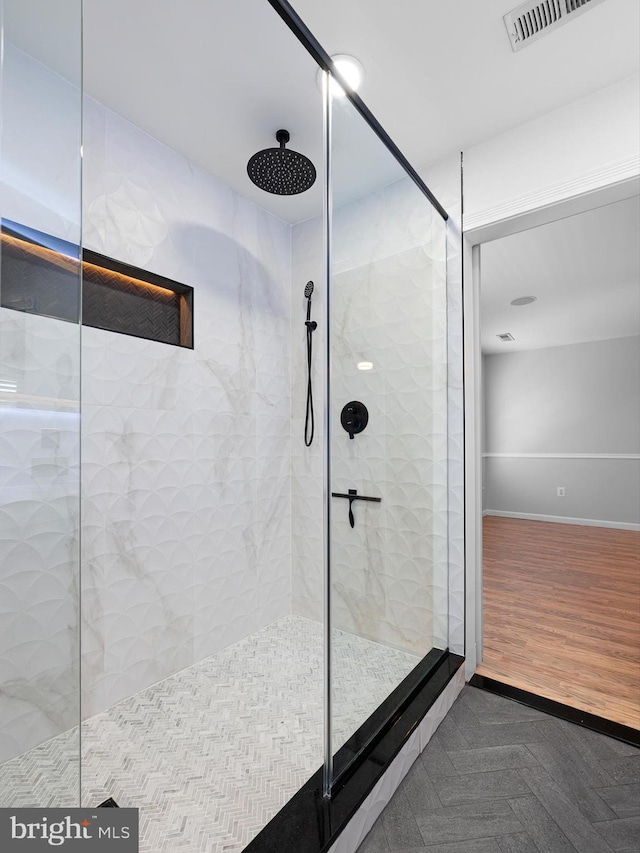 bathroom with visible vents, baseboards, walk in shower, and wood finished floors