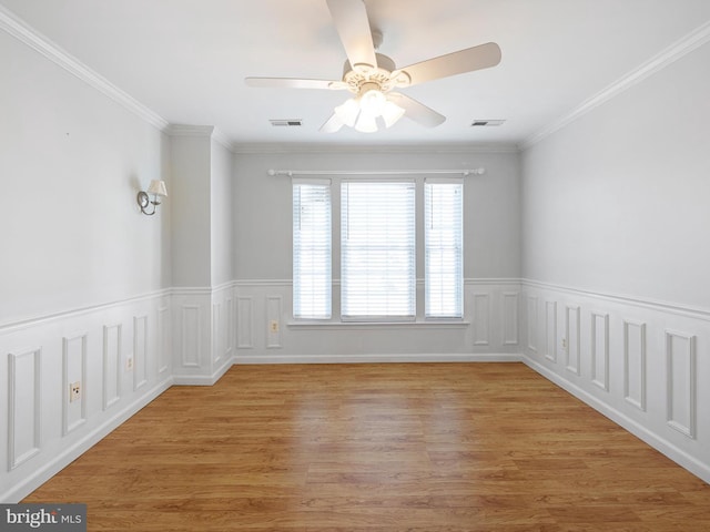 spare room featuring a ceiling fan, light wood-style floors, visible vents, and ornamental molding