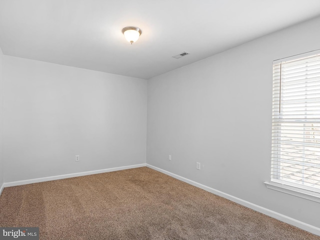 unfurnished room with visible vents, carpet floors, and baseboards