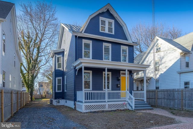 view of front of property with a gambrel roof, a porch, and fence