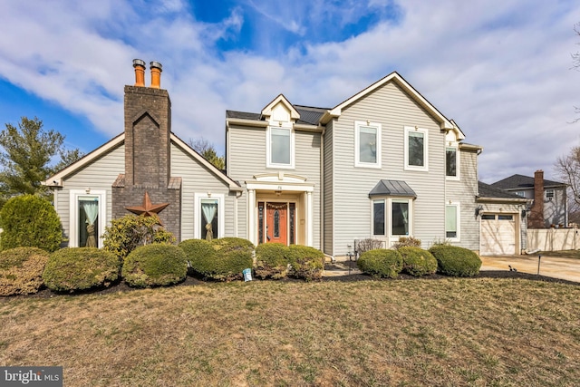 traditional-style house with a front yard, an attached garage, driveway, and a chimney