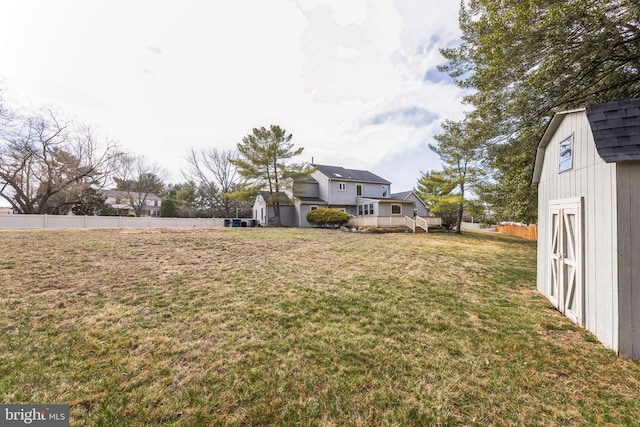 view of yard with a storage shed, an outbuilding, and fence