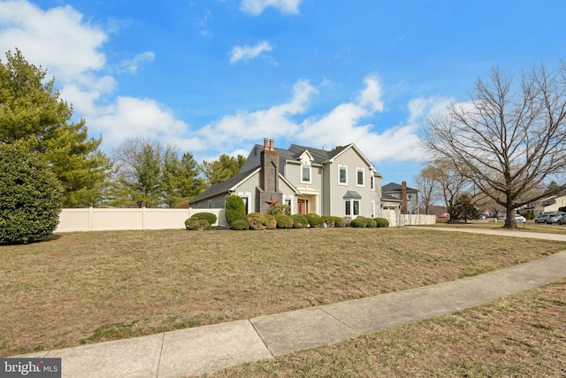 view of front of house with a garage, a chimney, a front yard, and fence