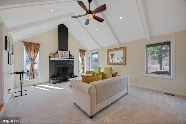 living area with visible vents, beam ceiling, a large fireplace, light colored carpet, and ceiling fan