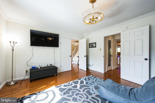 living area featuring stairs, a notable chandelier, wood finished floors, and crown molding