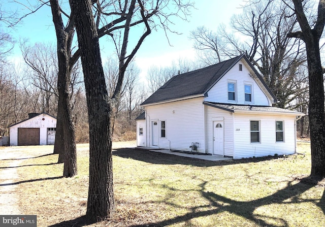 view of side of property with a yard, a detached garage, an outdoor structure, and a shingled roof