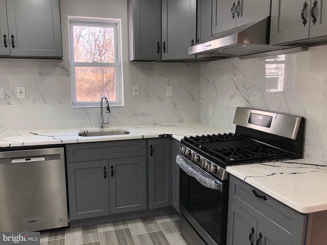 kitchen featuring a sink, appliances with stainless steel finishes, exhaust hood, and gray cabinetry