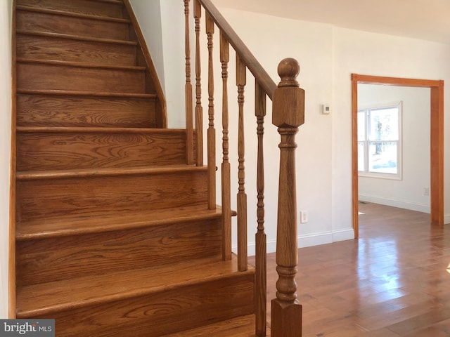 staircase featuring wood finished floors and baseboards