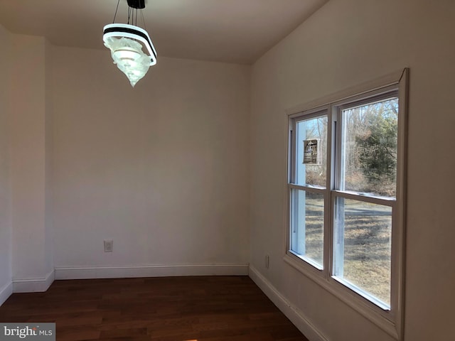 unfurnished dining area with dark wood finished floors and baseboards