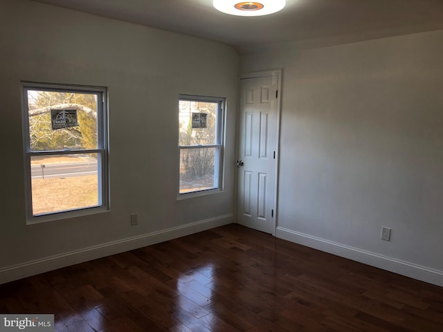 unfurnished room with baseboards and dark wood-style flooring