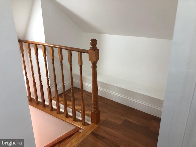 stairs with wood finished floors and vaulted ceiling