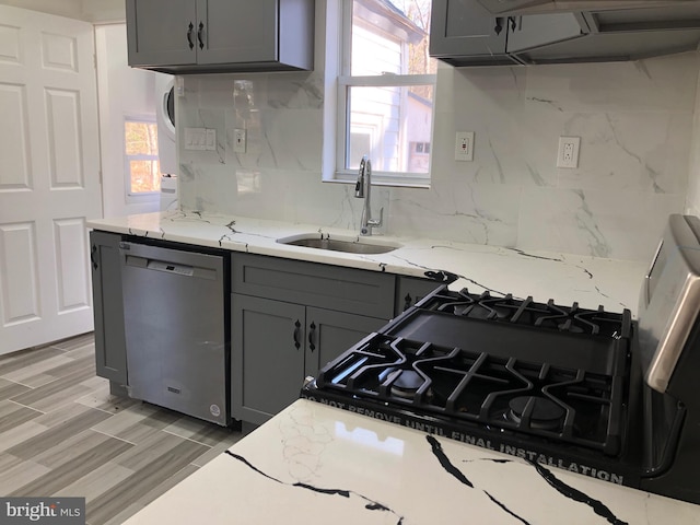 kitchen with a sink, tasteful backsplash, stainless steel dishwasher, and gray cabinets