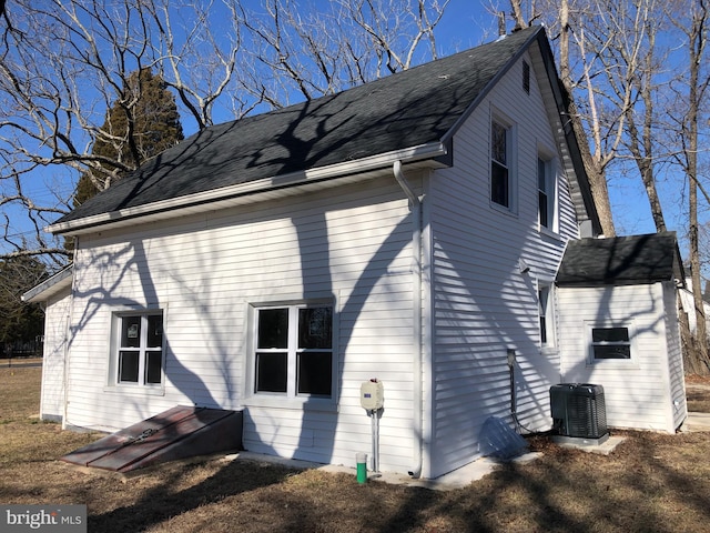 view of home's exterior with central AC unit and roof with shingles