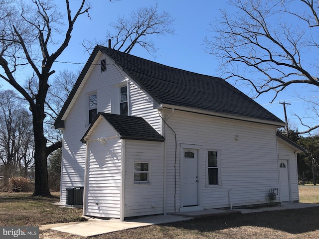 rear view of house with central AC and roof with shingles