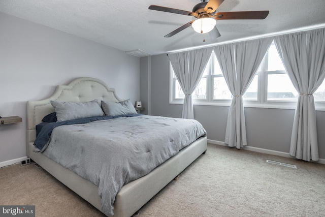 bedroom featuring a ceiling fan, visible vents, baseboards, a textured ceiling, and light colored carpet