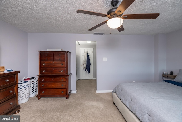 bedroom with visible vents, light colored carpet, a textured ceiling, and baseboards