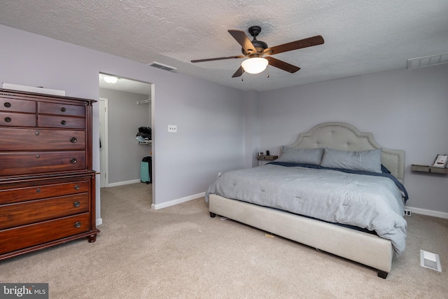 bedroom with light carpet, visible vents, a textured ceiling, and baseboards