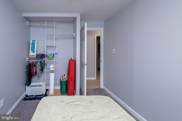 bedroom with a closet, baseboards, carpet floors, and an AC wall unit